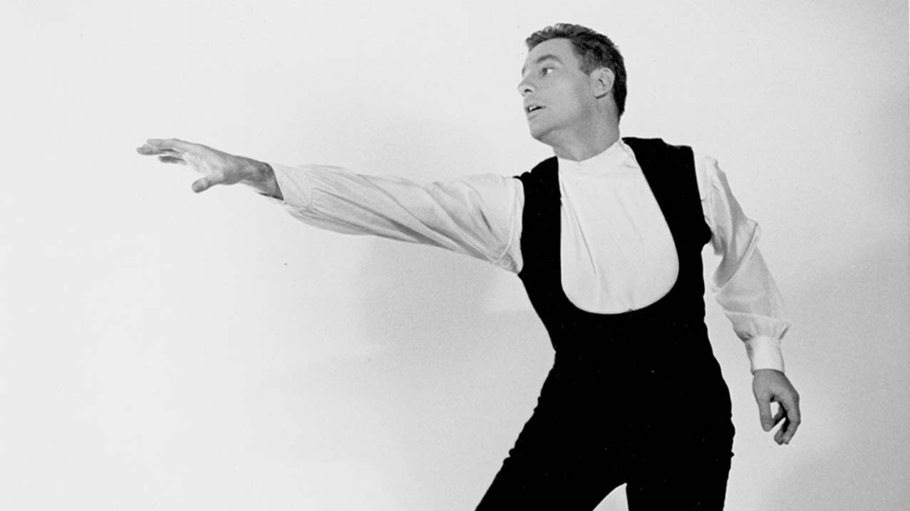 A younger Rod Strong in black and white holds a dance pose in front of a white background