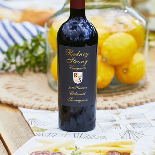 A bottle of Rodney Strong Reserve Cabernet on a picnic table set with a vase of lemons and picnic accessories