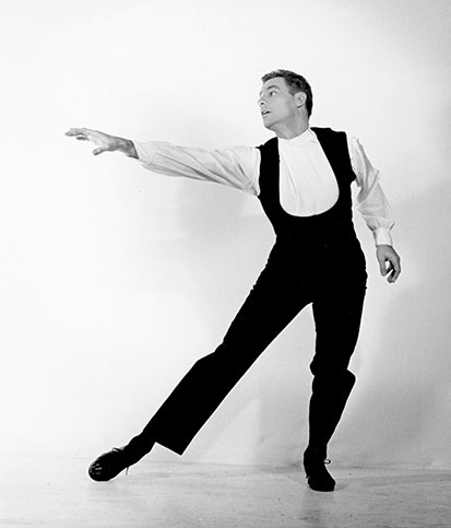 A young Rod Strong holds a dance pose while wearing dance clothes in front of a white backdrop