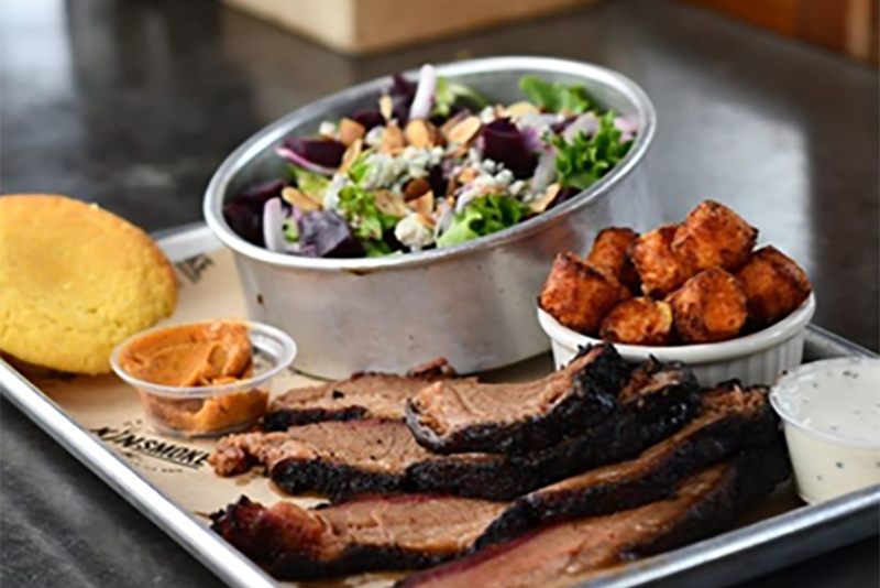 A metal tray of southern barbecued food from KinSmoke including tots, brisket and salad