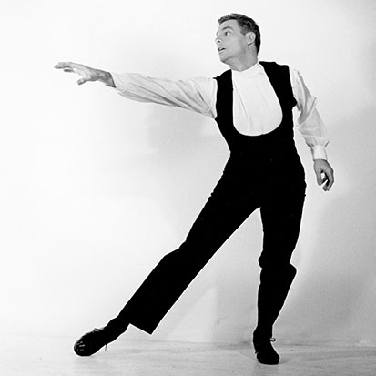 A young Rod Strong holds a dance pose while wearing dance clothes in front of a white backdrop