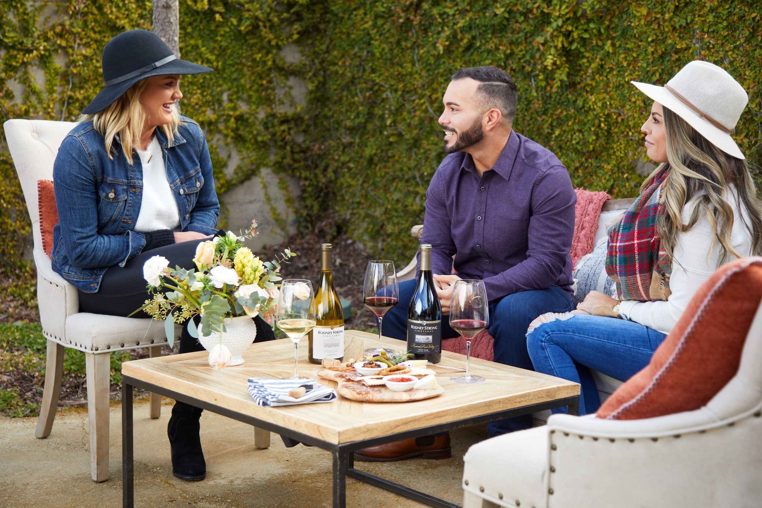 Three people having wine and snacks outdoors