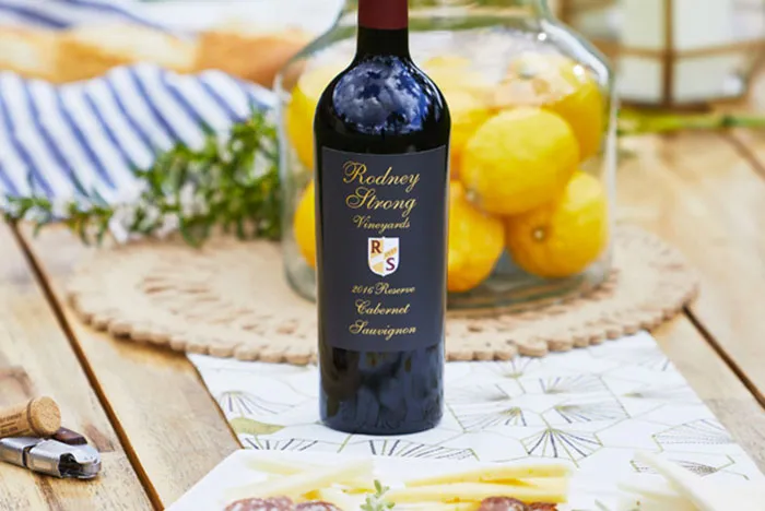 A bottle of Rodney Strong Reserve Cabernet on a picnic table set with a vase of lemons and picnic accessories