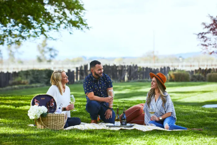 Group of people enjoying Rodney Strong wine on a blanket in the grass