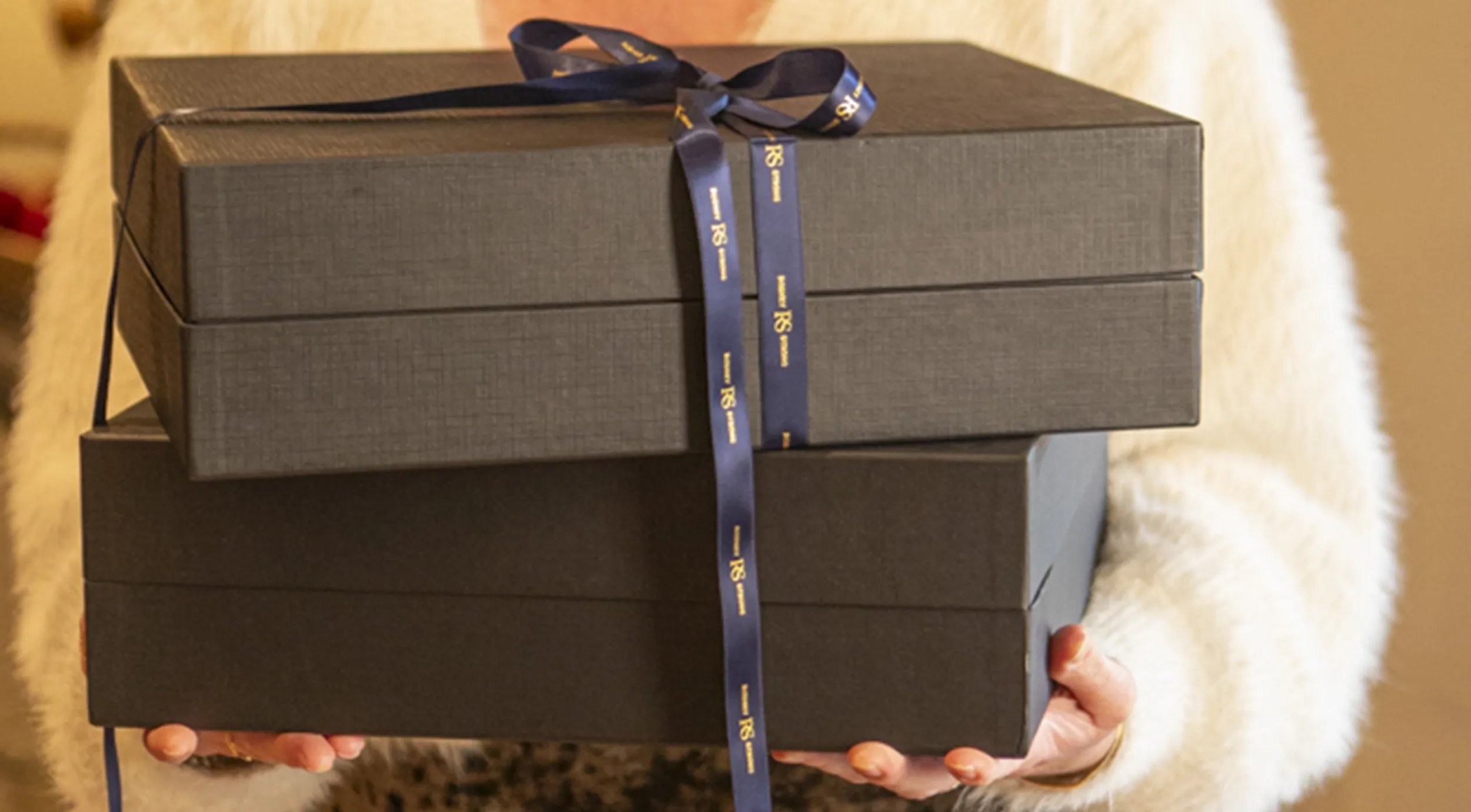 Woman carrying two black wine boxes with navy Rodney Strong ribbons